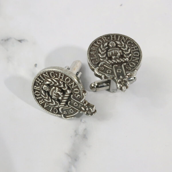 A pair of Gaelic Themes Clan Crest Lapel Pins with a coin on them.