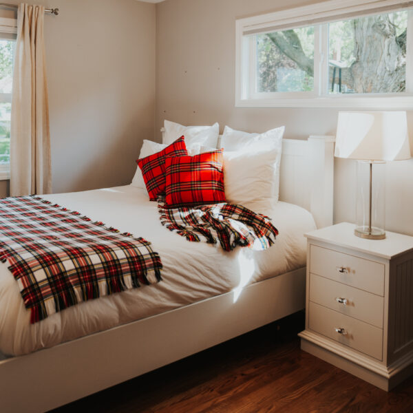 A white bed with a plaid Homespun Tartan blanket/throw.