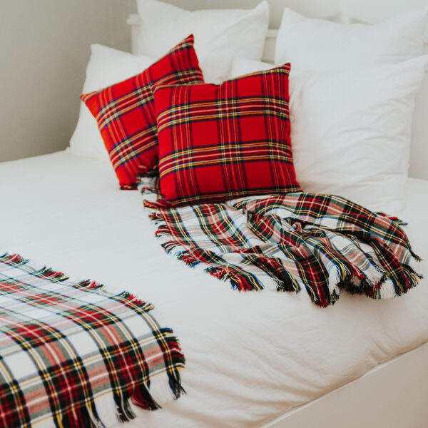 A bed with a Homespun Tartan Blanket/Throw on it.