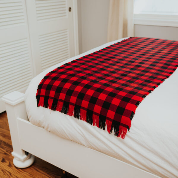 A bed with a red and black Homespun Tartan Blanket/Throw.