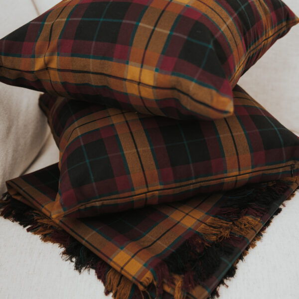 Three plaid pillows stacked on top of each other, showcasing the cozy charm of a Homespun Tartan Blanket/Throw.