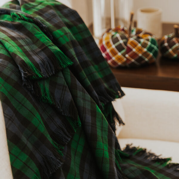 A green and black Homespun Tartan blanket/throw on a couch.