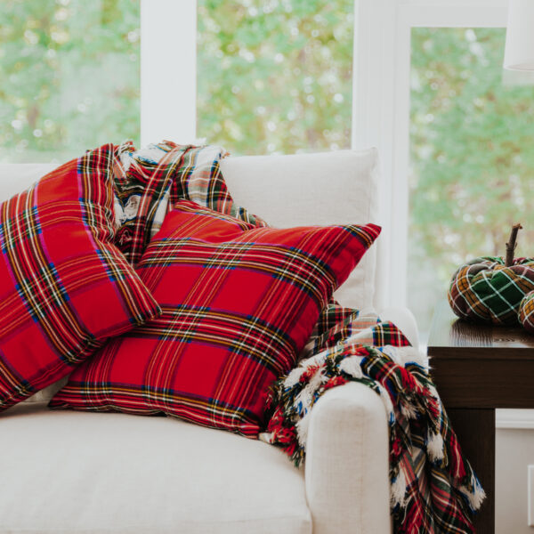 Homespun tartan blanket/throw pillows on a white couch.