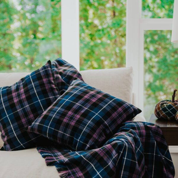 A Homespun Tartan Blanket/Throw on a couch in front of a window.