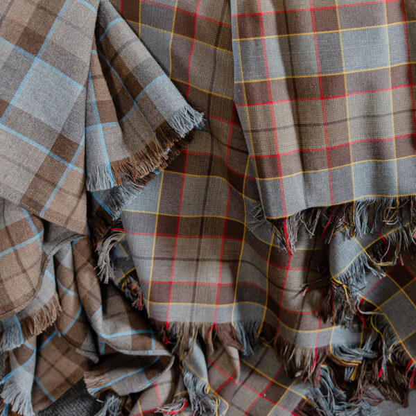 A group of OUTLANDER Throw/Blanket Authentic Premium Wool Tartan blankets laying on top of each other.
