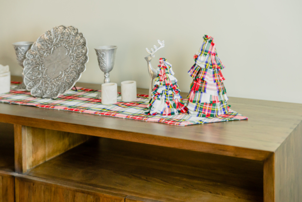 A wooden TV stand adorned with Tartan Christmas Tree - Homespun Wool-Blend decorations.