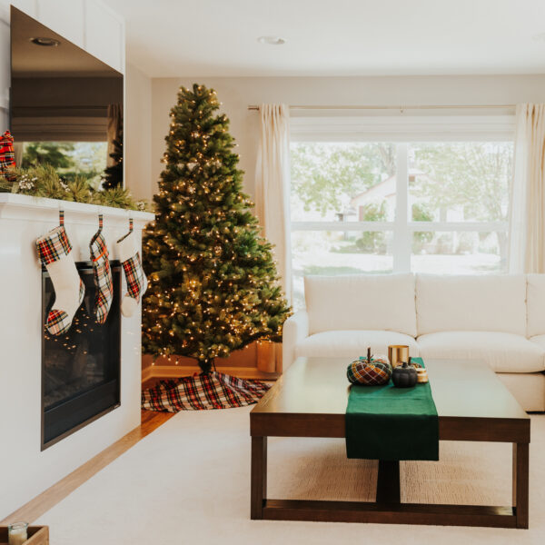A white living room with a Christmas tree adorned with Tartan Stocking with Toes - Homespun Wool Blend.