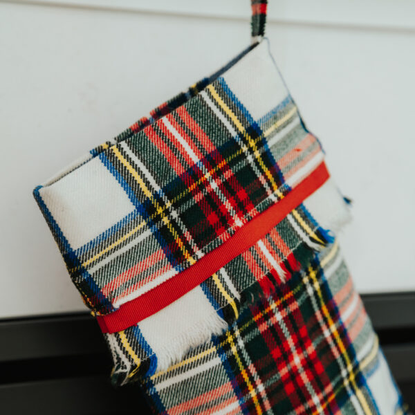 A Tartan Stocking with Toes - Homespun Wool Blend hanging on a fireplace.