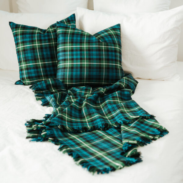 Two Homespun Tartan Blanket/Throws adorned on a bed.