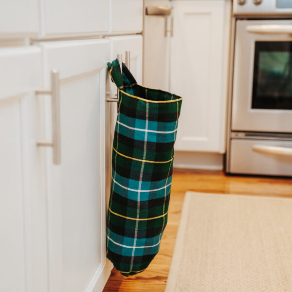 A Tartan Plastic Bag Holder - Homespun Wool Blend hanging on a kitchen door.