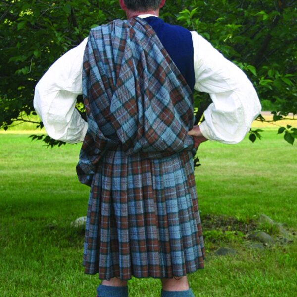 A man wearing a Great Kilt Cheater Pleats with pleats is standing in a grassy area.