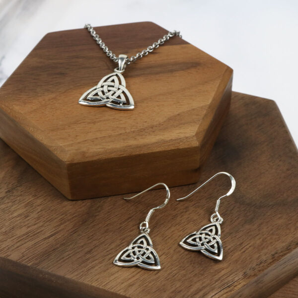A Trinity Knot Set, consisting of a necklace and earrings, displayed elegantly on a wooden box, is the product name.