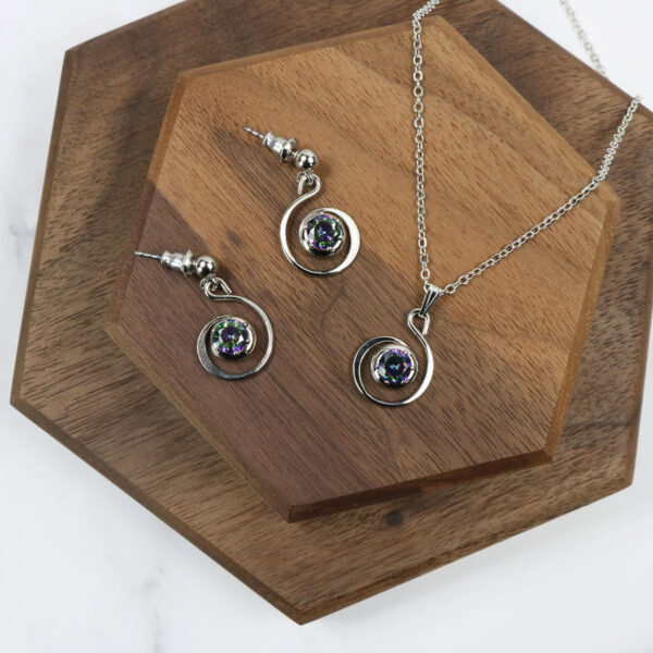 A silver necklace and Triquetra Sterling Silver Earrings set on a wooden table.