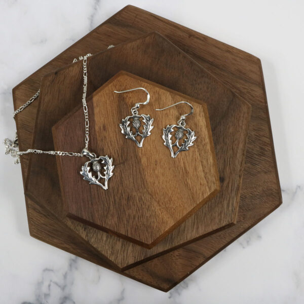 A set of Scottish thistle earrings and a Scottish Thistle Necklace on a wooden board.