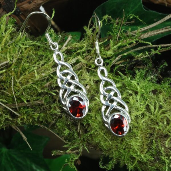 A pair of sterling silver Tree of Life Earrings with garnet stones.