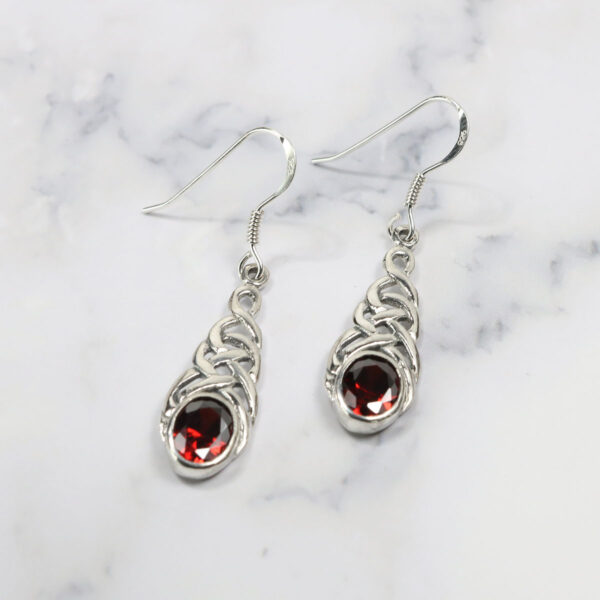 A pair of Triquetra Sterling Silver Earrings with a red stone.
