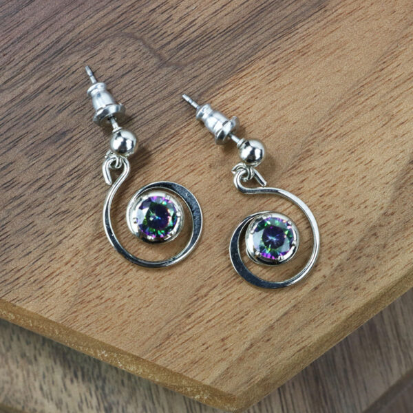 Mystic Crystal Spiral Earrings resting on top of a wooden table.