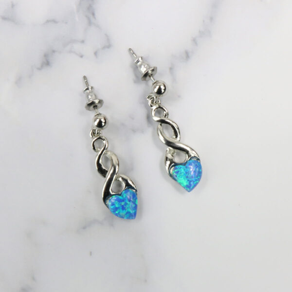 A pair of blue opal earrings, featuring Triquetra Sterling Silver Earrings, on a marble surface.