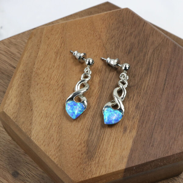 A pair of blue opal Triquetra Sterling Silver Earrings on a wooden table.
