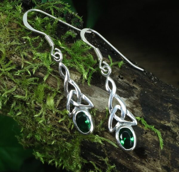 A pair of sterling silver earrings with emerald stones in a Green Triquetra Earrings design.