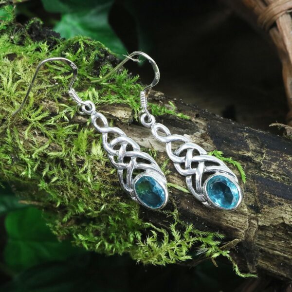 A pair of sterling silver Tree of Life Earrings with blue topaz stones.