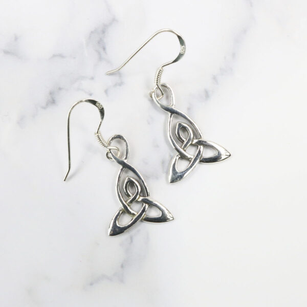 A pair of Triquetra Sterling Silver Earrings on a marble surface.