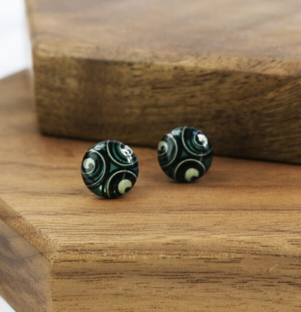 A pair of Opal Knot Stud Earrings on a wooden table featuring a knot design.