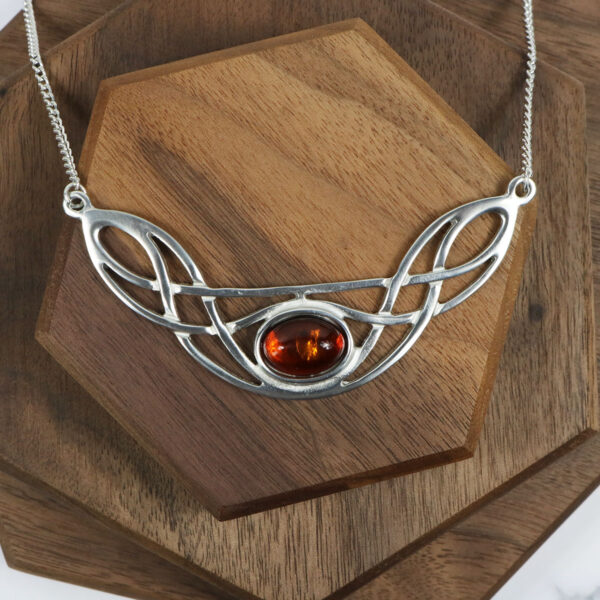 An Amethyst Celtic Knot Necklace with an amber stone on it.