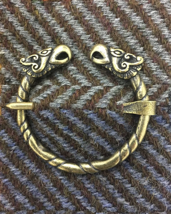 A pair of viking cufflinks on a tweed background.