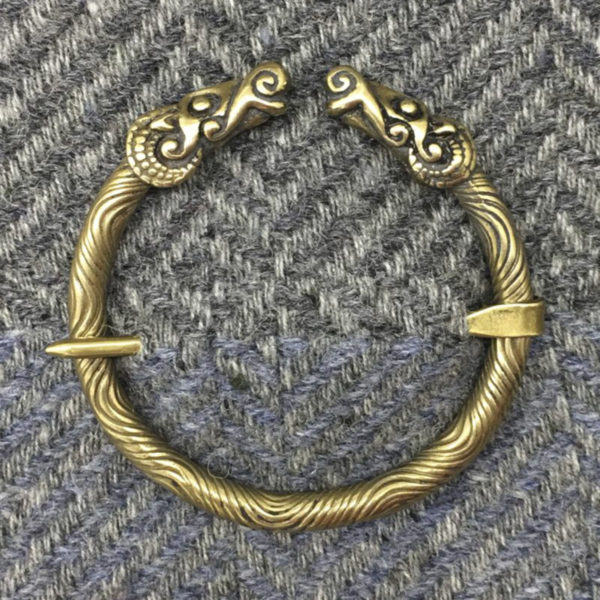 A brass bracelet with two horns on it.