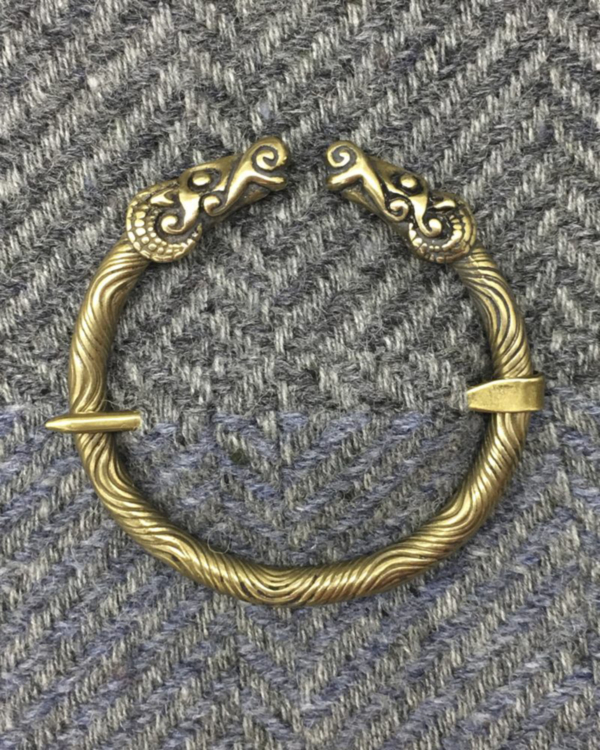 A brass bracelet with two horns on it.