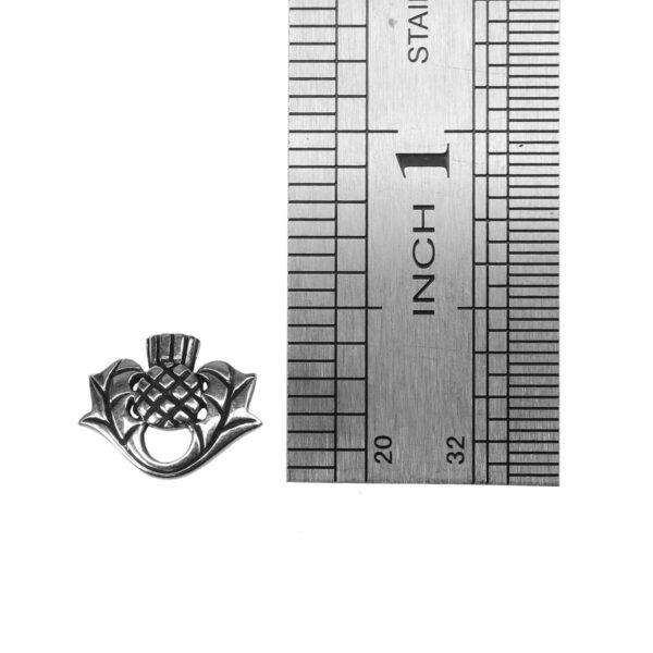 A Luckenbooth Thistle Brooch with a ruler next to it.