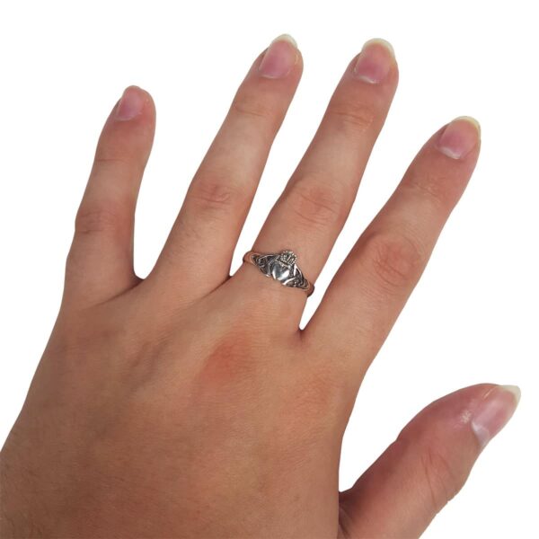 A woman's hand adorned with a silver Triquetra Claddagh ring.