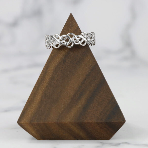 The Tangled Celtic Knot Ring is sitting on top of a wooden triangle.