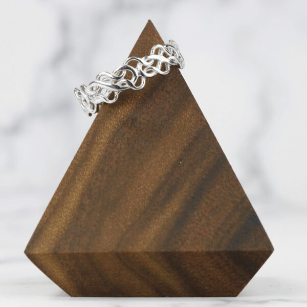 A Tangled Celtic Knot Ring on top of a wooden triangle.
