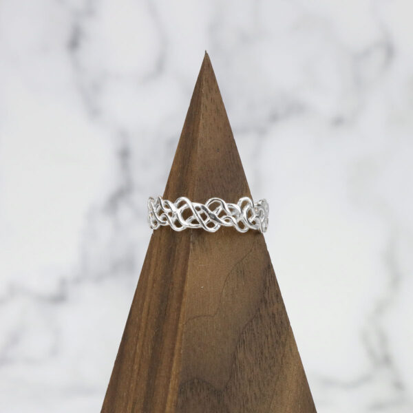 A *Tangled Celtic Knot Ring* resting on top of a wooden block.