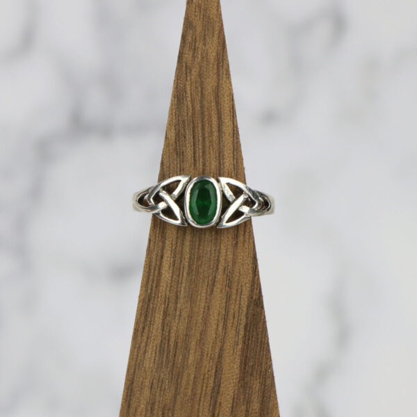 A sterling silver ring with a Two Tone Eternity Knot Band and an emerald stone.