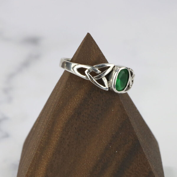 A Two Tone Eternity Knot Band with a sterling silver base and emerald stone.