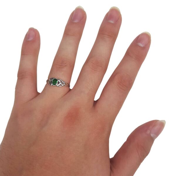 A woman's hand holding a stunning Emerald Green Trinity Knot Ring.