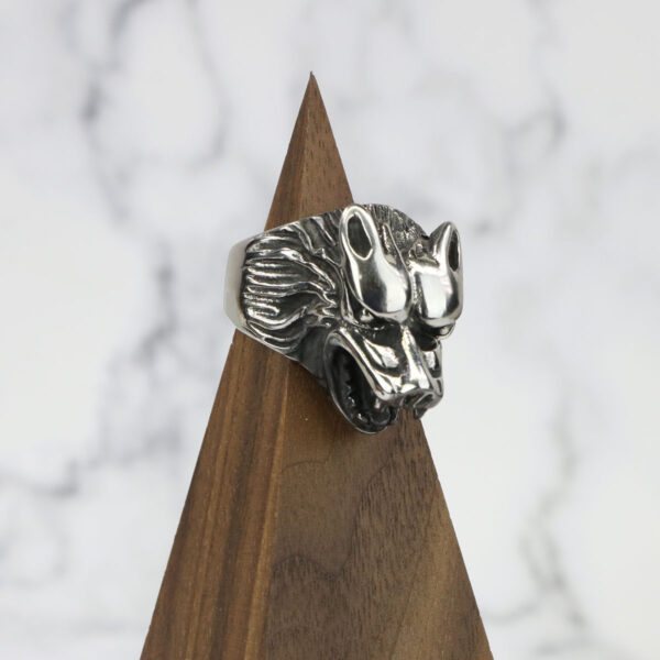A silver Dire Wolf Stainless Steel Ring on top of a wooden base.