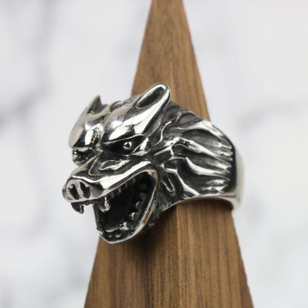 A Dire Wolf Stainless Steel Ring resting on a wooden base.