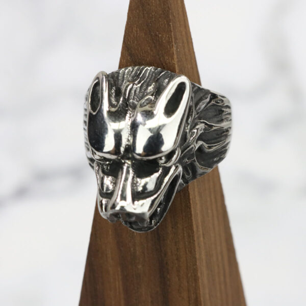 A silver Dire Wolf Stainless Steel Ring on a wooden base.
