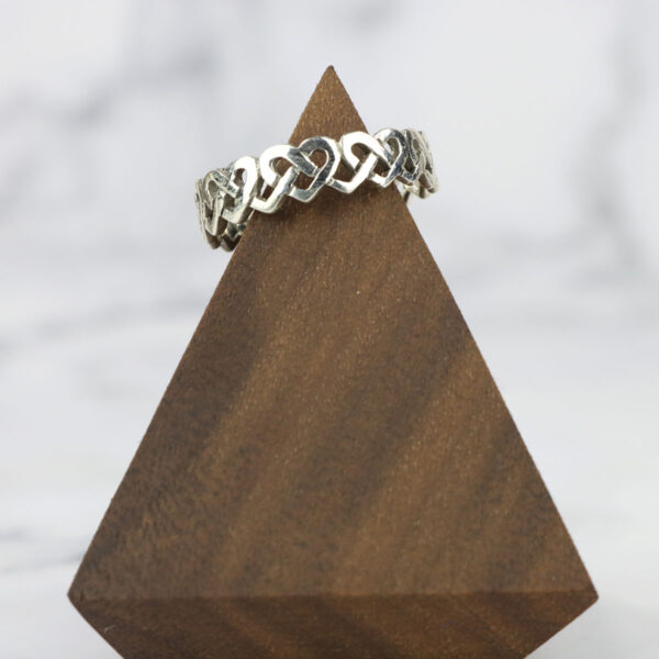 A large silver Large Celtic Knot Spinner Ring resting on top of a wooden block.