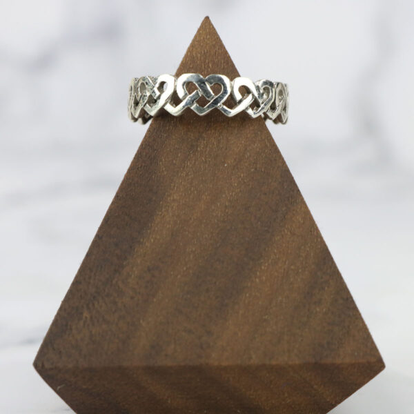 A large Celtic Knot Spinner Ring on top of a wooden triangle.