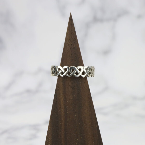 A Large Celtic Knot Spinner Ring featuring a celtic knot design, made from sterling silver and placed on top of a wooden base.