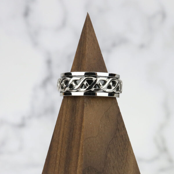 A Celtic Knot Spinner Ring-Size 13 with a celtic knot design on top of a wooden base.