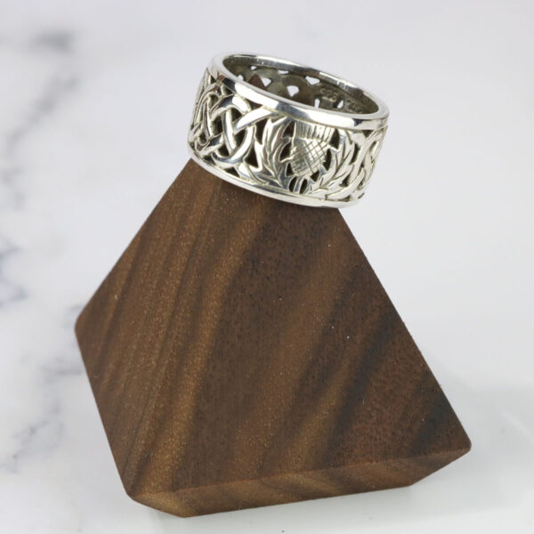 A silver ring with a Two Tone Eternity Knot Band on a wooden stand.