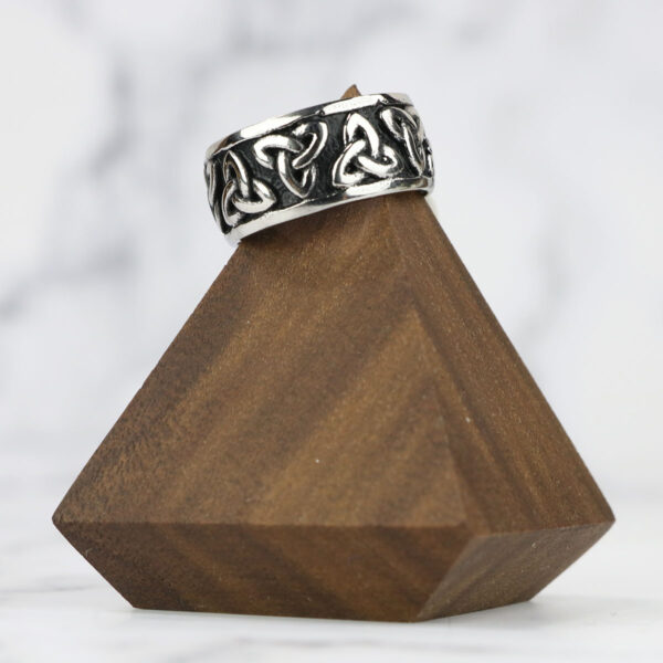 A Two Tone Triquetra Ring with a triquetra design resting atop a wooden block.