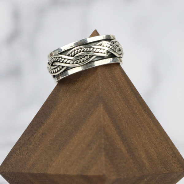 A Large Celtic Knot Spinner Ring with a braided celtic knot design on top of a wooden block.