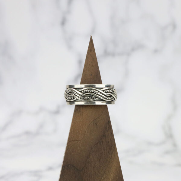 A Large Celtic Knot Spinner Ring sitting on top of a wooden block.